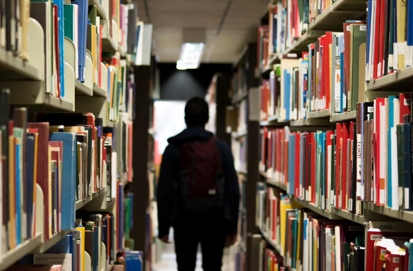 Student Walking through a Aisle of Books